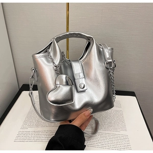 Détail du sac seau en cuir argenté métallisé avec breloque cœur et bandoulière chaîne