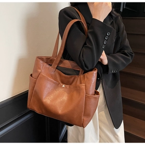 Detail view of brown soft leather tote bag with side pockets and magnetic buckle
