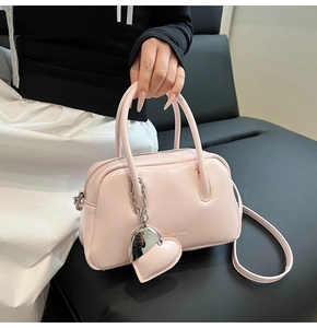 Detail view of pink Boston bag with glossy finish and sweet heart-shaped charm accessory