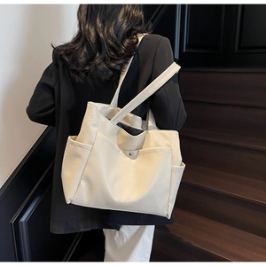 Detail view of cream oversized leather tote bag showing soft texture on a shoulder