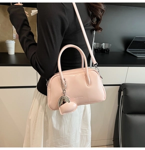 Pink glossy pillow bag shown on model with heart pendant and adjustable strap
