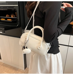 Détail d'un sac cylindrique en cuir blanc cassé avec pendentif cœur dans une cuisine moderne