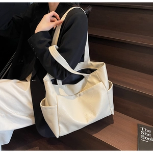 Detail view of cream oversized tote bag in wrinkled glossy leather worn by a model