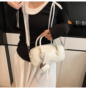 Détail du sac polochon blanc brillant avec pendentif coeur et logo de marque CLEAR*K
