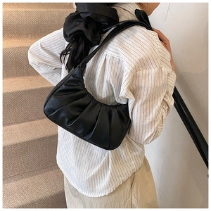 Détail du sac nuage en cuir noir froncé porté à l'épaule par un mannequin élégant