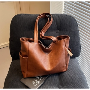 Detail of soft brown leather tote bag with vintage texture and side pocket on a chair