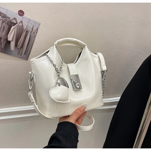 Détail du sac seau crème avec boucle argentée et charm en forme de cœur décoratif
