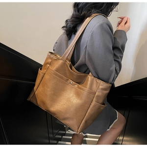 Detailed view of dark brown soft leather tote bag showing textured finish and silver buckle