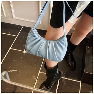 Détail d'un sac à bandoulière croissant bleu clair plissé avec des plis verticaux nets