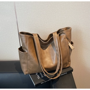 Detail view of brown soft leather tote bag with side pocket and textured finish