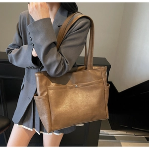 Close-up of a large brown soft leather tote bag with functional silver snap pocket