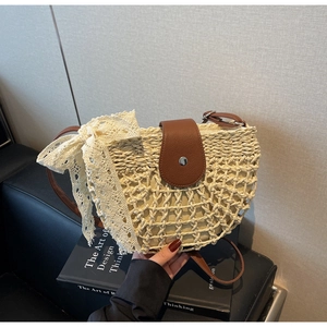 Detail der Stroh-Satteltasche mit dunkelbrauner Lederklappe und großer weißer Spitzenschleife