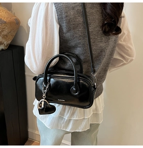 Vue détaillée d'un sac polochon noir brillant élégant avec charm coeur et bandoulière