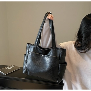 Fashionable black large capacity tote bag shown on shoulder with minimalist street style
