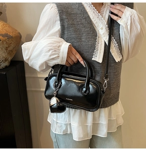Vue détaillée du sac polochon en cuir noir brillant avec logo CLEAR★K et breloque coeur