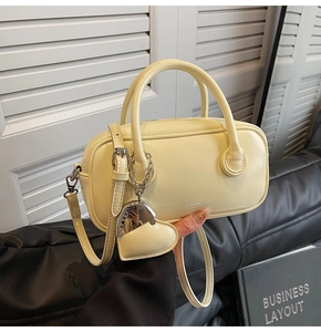 Détail du sac polochon crème avec breloque cœur et maillons métalliques argentés
