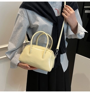 Close-up of a pale yellow glossy leather Boston bag with gold hardware and shoulder strap
