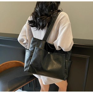 Detail of black faux leather tote bag with silver rivets and external side pockets