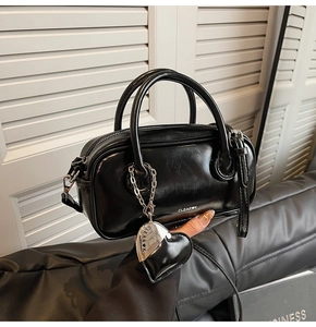 Détail du mini sac Boston en cuir verni noir avec breloque cœur et finition brillante