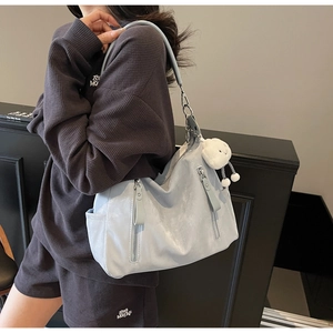 Détail du grand sac hobo bleu clair avec fermetures éclair et breloque en peluche