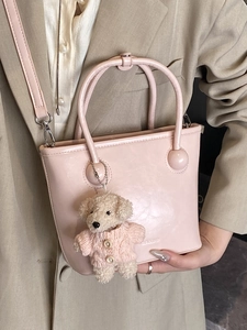 Minimalist light pink bucket bag with round handles and a cute puppy charm accessory
