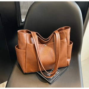 Close-up of brown soft leather tote bag with functional side pockets on leather seat