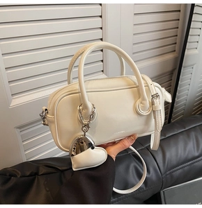 Détail du sac Boston blanc avec poignée et pendentif en forme de cœur avec logo de marque