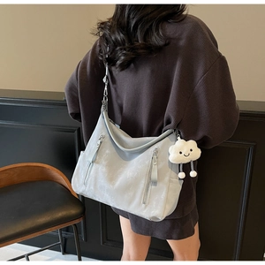 Détail du grand sac cabas gris clair avec poches zippées et un pendentif nuage mignon