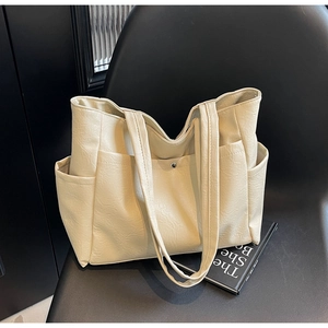 Detail view of cream soft leather tote bag showing side pockets and magnetic buckle closure