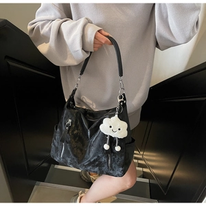 Détail d'un grand sac cabas noir à texture vieillie avec un pendentif nuage en peluche blanc