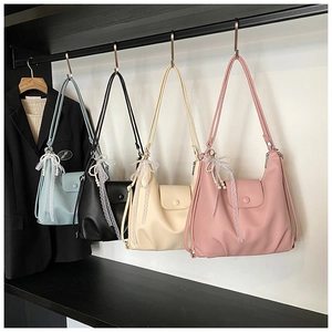 Detail view of colorful tote bags with lace bows and pearl charms on a hanger