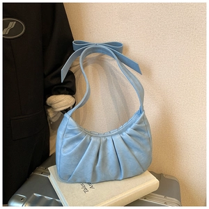 Détail d'un sac nuage plissé bleu ciel avec un nœud papillon sur une valise argentée