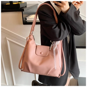 Detail view of pink lychee leather tote bag with pearl lace charm and magnetic snap closure