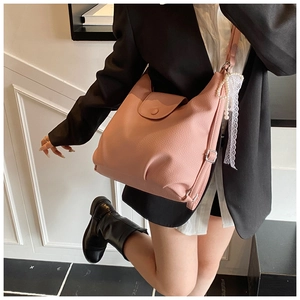 Detail view of pink lychee leather tote bag featuring pearl chain and lace charms
