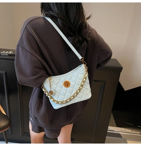 Detail of light blue quilted bucket bag with gold chain and circular metal clasp detail