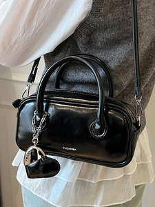 Sac polochon noir brillant avec pendentif coeur pour un porté croisé très polyvalent