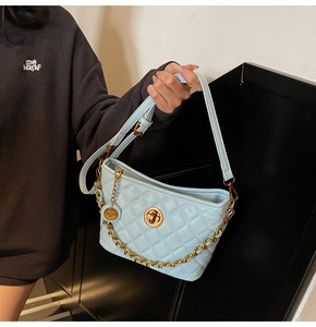 Detail showing the light blue quilted bucket bag with gold chain and metal twist lock closure