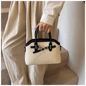 Détail d'un sac à main beige tissé avec garniture en cuir noir et fermoir argenté