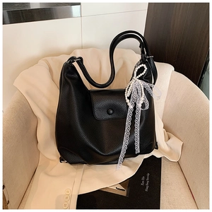 Close-up of black litchi grain leather hobo bag with pearl and lace bow pendant