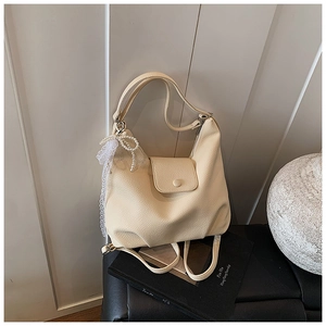 Detail of cream lychee leather tote with pearl bow charm and convertible straps