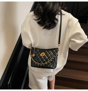 Detail of black quilted bucket bag with gold chain strap and metallic twist lock clasp