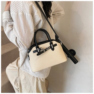 Détail du sac beige tissé avec poignée en cuir noir porté par un mannequin