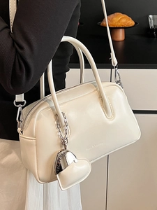 Minimalist creamy white glossy handbag with silver heart charm and crossbody strap