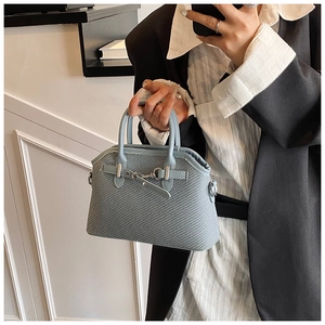 Détail du sac coquille bleu clair avec texture tissée et poignées rondes lisses