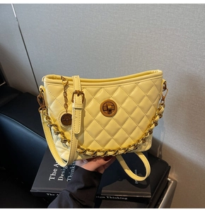 Detail of yellow quilted bucket bag with gold chain strap and metal turn-lock closure