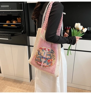 Detail of pink and beige woven tote bag featuring dragon embroidery and Chinese frog button