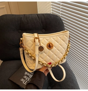 Detail of white quilted bucket bag with golden twist lock and thick metal chain strap