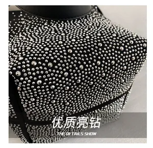 Macro shot of high-quality silver rhinestones embedded on a black luxury shoulder bag surface