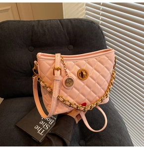 Macro detail of pink quilted bucket bag with golden twist-lock and metal chain strap