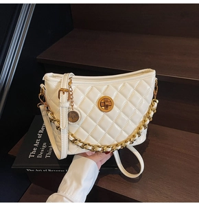 Detail of white quilted bucket bag featuring a gold twist lock and dual chain strap